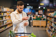 © Serhii - Concerned man checking grocery store receipt in supermarket