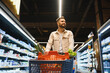 © Serhii - Young man shopping for groceries in supermarket aisle