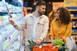 © Serhii - Couple shopping for groceries at modern supermarket