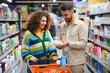 © Serhii - Couple shopping for household products in supermarket aisle