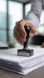 © Curioso.Photography - Businessman stamping an approval seal on a business contract document at an office desk.