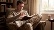 © K4VEE - A thoughtful man sits curled into a comfortable armchair with an open book in warm natural light, creating an intimate scene of concentration and quiet reflection.