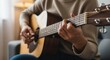 © Eve - Close up of female hands playing acoustic guitar at home. Woman practicing musical instrument, strumming chords on wooden guitar. Hobby, music education, creative lifestyle and leisure concept.