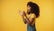 © Vasiliy - Surprised young Black woman looking to the side. Amazed female with curly hair and denim overalls against yellow background. Reaction and shock concept