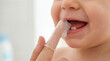 © Aurora Aesthetics - Parent brushing baby teeth silicone finger toothbrush hygiene copy space left dental care health parenting family routine close up portrait clean smile