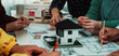 © InfiniteFlow - Team of architects engaged in a collaborative session, discussing building plans while showcasing a detailed model of a house, reflecting creativity and innovation. SACTR