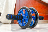 Close-up of ab roller with blue wheels on tiled floor