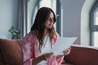 © Daniel - Serious entrepreneur freelancer woman indoor reading attentively paper letter official document seated on sofa alone at home, analyzing information, learn contract details, check report concept