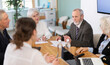 © JackF - Elderly man sits at conference table leading business meeting with group of elderly men and women