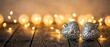 © Yuliia - Silver decorative Christmas ornaments with intricate patterns on rustic wooden surface surrounded by warm golden bokeh lights creating festive holiday atmosphere.