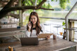 © apichat - Asian woman remote working talking on smartphone outdoors