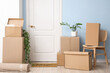 © Pixel-Shot - Chair with cardboard boxes and plants near door in hallway on moving day