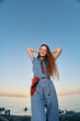 © SHOTPRIME STUDIO - joyful woman in modern boho-western denim outfit smiling outdoors at sunset with film color, casual lifestyle, street style, relaxed atmosphere