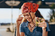 © SHOTPRIME STUDIO - Lifestyle woman with modern boho-western denim street style smiling happily while holding a drink, relaxed outdoor setting, film color tone enhancing natural mood.