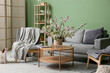 © Pixel-Shot - Sofa with armchairs, coffee table and vase of blooming branches near green wall in living room
