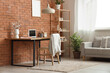 © Pixel-Shot - Interior of office with workplace, blossoming branches in vase and sofa