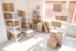 © Pixel-Shot - Interior of light warehouse with hand truck and cardboard boxes on shelving units