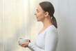 © Pixel-Shot - Beautiful young woman with cup of hot coffee in kitchen