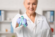 © Pixel-Shot - Mature female doctor with teal ribbon in clinic. Cervical Health Awareness Month