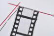 © nahhan - A hand knitted piece of fabric features a creative design mimicking a black and white vintage movie film strip on red knitting needles