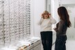 © Roman - Senior woman trying on new eyeglasses in optical store