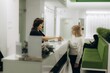 © Roman - Medical administrator helping patient at clinic reception desk