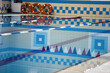 © Aleksandr - An indoor swimming pool with blue and white tile is seen, featuring lane dividers and several orange safety rings hanging on the wall. Plenty of space for text.
