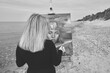© TRAVELARIUM - Young woman painting self-portrait on easel at peaceful beach setting