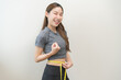© KMPZZZ - Diet, slim shape asian young woman, female standing, hand using measure tape around waist, body. Happy girl slim slender isolated on background. Diet session for wellbeing health, eat good food people
