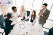 © deagreez - Business team collaborating in the office, shaking hands in a group setting while enjoying successful project outcomes