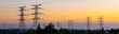 © ABCDstock - High voltage electricity pylons and transmission lines at sunset. Power grid and energy infrastructure industry concept.