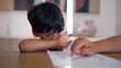 © Marco - Young boy struggling to focus on homeschooling worksheet, absentmindedly pointing at paper, feeling bored and distracted while trying to stay engaged in learning at home
