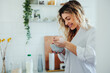 © bernardbodo - Blonde woman smiling while making breakfast in a bright home kitchen enjoying a relaxed morning routine