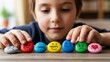 © El_design - Child arranging colorful emotion stones with faces and words for emotional learning activity background or classroom resource banner
