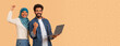 © Prostock-studio - Two young adults smile and cheer while standing together. One wears a headscarf, and the other holds a laptop. They seem happy and excited about an achievement in their workspace.