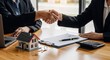 © TheseusStock - Professional Business Handshake for Real Estate Agreement with Model House on Wooden Desk