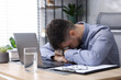 © New Africa - Man feeling fatigue at wooden desk in office