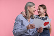 © New Africa - Little girl greeting her grandmother with holiday card on pink background, space for text