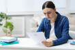 © New Africa - Worried woman with rejection letter from university at white table indoors. Space for text