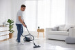 © New Africa - Man cleaning floor with vacuum cleaner at home