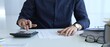 © volha_r - Businessman in a blue shirt examining financial documents at an office desk, using a calculator amidst paperwork and folders. Audit and taxes, business concept
