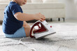 © New Africa - Child safety at home. Little boy playing with iron indoors, closeup. Space for text