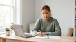 © Matt - Woman writing in notebook at home desk with laptop and water bottle