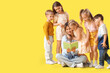 © Pixel-Shot - Group of little children with nursery teacher reading story on yellow background