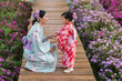 © geargodz - woman and child girl in yukata (kimono dress) holding hand together with flower blooming in garden