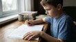 © OlgaKon - Young boy studying and writing in notebook at wooden desk indoors