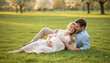 © Vyatcheslav - Pregnant woman and man lying on green grass in a park during golden hour. Happy couple expecting a baby. Maternity portrait in nature with warm sunset light