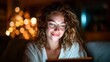 © svastix - A young woman with glasses smiles while using her tablet in a warm, inviting atmosphere, highlighting the pleasure of technology combined with comforting surroundings during the night.