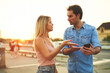 © Teodor Lazarev - Two young adults engage in a heated discussion on a bustling street at sunset. The warm glow of the evening light sets the backdrop for their intense exchange