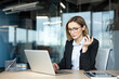 © Liubomir - Businesswoman thinking critically while working on a laptop, facing a complex problem or project in a modern office environment, contemplating solutions with a focused and frustrated expression
